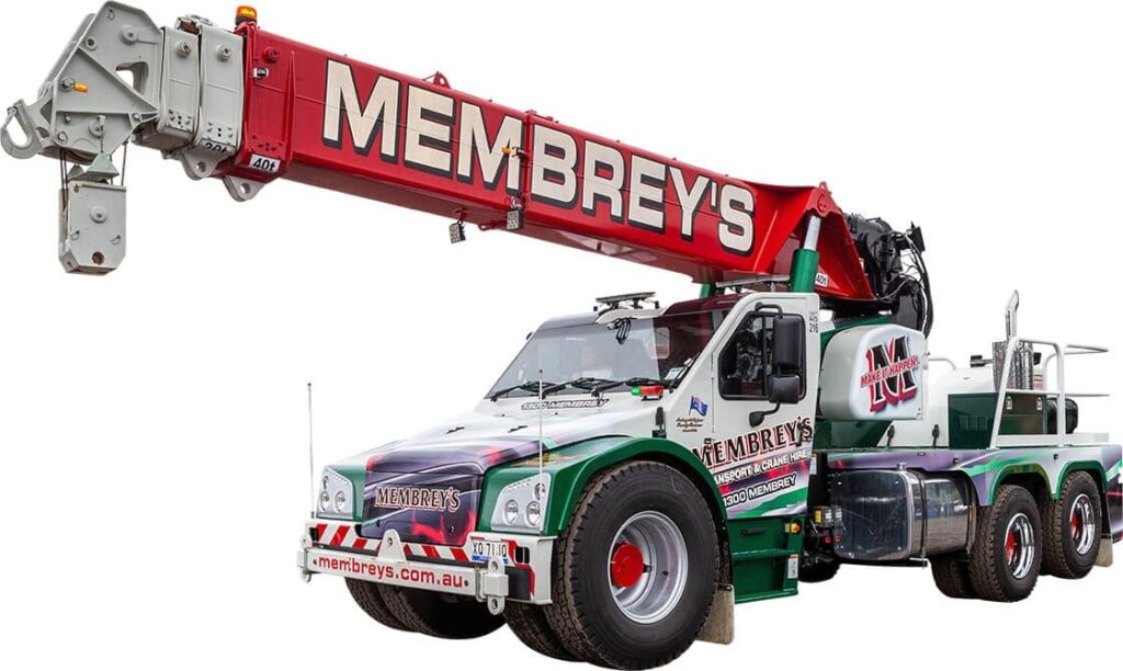 A large truck-mounted crane with "Membrey's" in bold red letters on the crane arm, featuring green and white colors, multiple tires, and stabilizers for lifting heavy loads.